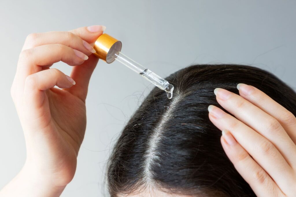 Women applying hair oil on her scalp